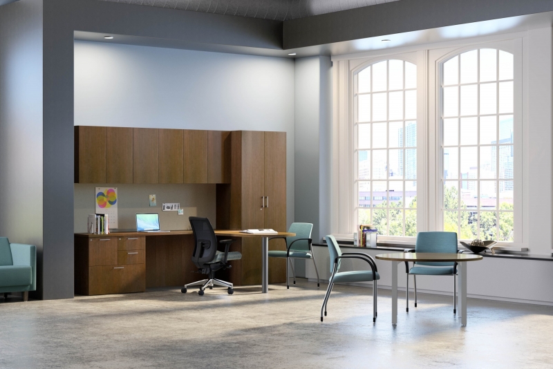 large room in an office with a table that has two blue chairs seated at it as well as a wall of dark brown storage safe cabinets