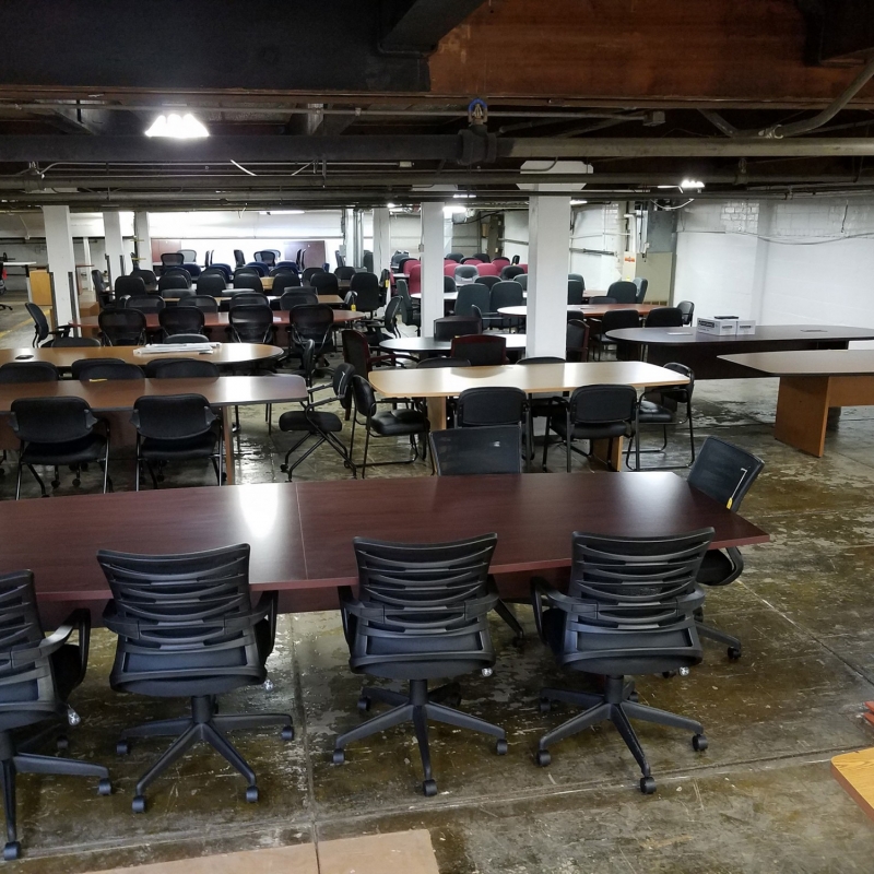 Overhead shot of showroom containing multiple conference tables of varying lengths and colors lined with office chairs
